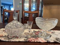 Wide view of all three items on table showing candy dish with lid, liqueur glass, and compote bowl.