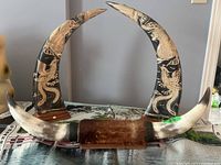 Photo of two large carved decorative horns with dragon and phoenix carvings, mounted on wooden stands