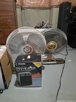 Photo showing two metallic fans and a boxed Philips Fan/Heater unit.