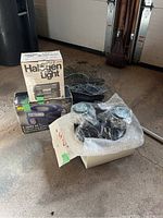 Full lot overview showing curling lights in box, halogen light box, black nets, and packaging material on concrete floor