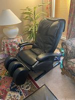 Front angle view of black electronic massage chair showing peeling vinyl upholstery and foot massage sections.