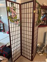 Three-panel wood and paper folding screen with faux purple flowers and green leaves attached.