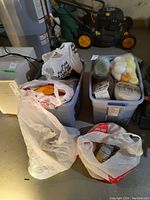 Two plastic bins filled with yarn and wool skeins along with plastic bags containing more yarn.