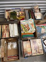 Top view of multiple open boxes containing vintage magazines, books, and stamps with varied paper materials and colors.