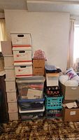 Stack of boxes and plastic bins holding fabric, fiberfill, and sewing materials