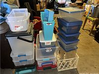 Full stack of various plastic storage containers and bins of different sizes and colors, stacked in a garage or storage room.
