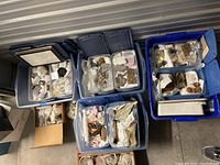 Overhead view of six blue plastic storage bins filled with various rock and mineral specimens wrapped and bagged