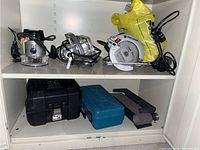 Photo showing tools on two cabinet shelves including Porter Cable router, circular saw, and power tool cases.