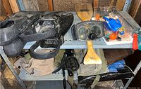 Two sets of scuba flippers, vintage scuba goggles, plastic container with vintage Scuba Steve action figure, decorative wooden oar beneath goggles