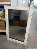 Photo of vintage framed mirror with ornate cream frame showing wear and age