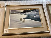 Framed art print featuring two wolves walking in snow near a river with forest in the background.
