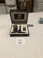 Full view of collectible US Army gift set with watch, pen, keychain inside camouflage box on white surface.