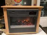 Front view of electric fireplace showing wood surround, vent, and faux log display with flame effect