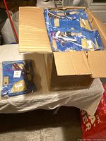 Cardboard box containing multiple sealed blue and tan fabric mats