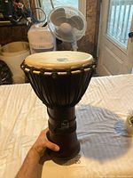 full height view of rope-tuned djembe drum held at base