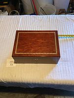 Top closed view of wooden humidor showing rectangular shape and decorative inlaid border