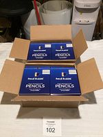 Opened box showing four stacks of blue Pencil Buddies boxes containing the pencil sets.
