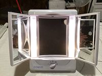 Front view of the Conair beauty mirror showing the center mirror and the two side mirrors unfolded with lighting switched on.