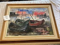 Framed oil painting showing boats at harbor with impressionistic style in bold brushstrokes and muted colors, with red sky background.