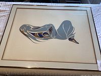 Front view of framed print depicting abstract mother and child design under glass in gold metal frame.