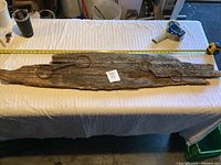 Full view of rustic home decor piece showing full length of wooden plank with two large metal scissors mounted on it, placed on table with measuring tape.