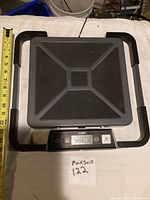Top view of the Dymo shipping scale showing textured black platform and surrounding frame with a tape measure for size reference.