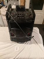 Front view of LG DJ Party speaker system showing speaker grills, power cord draped on front, and control panel with buttons and dials.