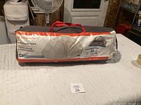 Image of the tent bag showing brand name Outbound, product name Cache 4-Person Tent with carrying handles.