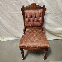 Full front view of antique Eastlake chair showing mahogany wood frame and vintage patterned upholstery on seat and backrest.