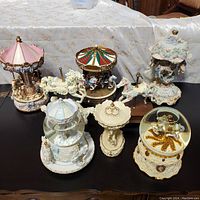 Full set of eight decorative music-themed pieces displayed on a table including carousels, carousel horses, and snow globes, showing colors, base details, and overall design.
