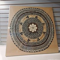 Full frontal photo of framed round bark paper folk art with concentric circles and floral design in black and white.