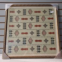 Full view of framed fabric artwork showing geometric patterns and ornate frame corners.
