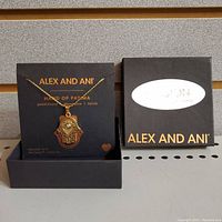 Front view of the Hand of Fatima necklace on packaging with original box beside it.