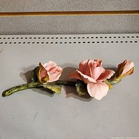 Full view of a 7 inch porcelain rose branch with three pink roses and green leaves on a stem