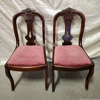 Front view of both Victorian chairs showing mahogany frames and pink velvet seats.