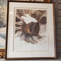 Framed art print showing rustic wooden wagon wheel against a neutral background, in a wooden frame with double matting.