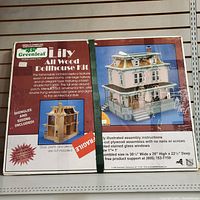 Box front of Greenleaf Lily All Wood Dollhouse Kit showing full color photo of assembled Victorian style dollhouse and product details.