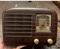 Front view of the antique radio showing the tuning dial, brand name, two knobs, and grill design.