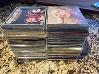 Two stacks of CDs in jewel cases viewed from above, showing album artwork and spines.