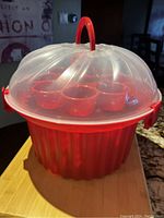 Full assembled cupcake carrier with clear dome lid and red handle on top, showing overall appearance and size.