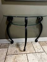 Front view of the glass and metal console table showing the curved legs and two glass shelves.
