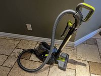 Full view of Hoover WindTunnel bagless vacuum cleaner with hose and handle on tiled floor