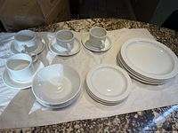Full set of 16 pieces displayed on a white cloth showing all components including dinner plates, side plates, bowls, and teacups with saucers.