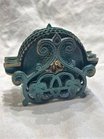 Close-up photo of ornate brass stand with fleur de lis motif and detailed vintage patina.