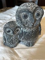 Front and side view of a vintage Nuvuk owl soapstone carving showing two owls with detailed white accents and texturing.