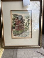 Full photo of the framed print showing detailed illustration of Victorian houses, black iron fence, trees, and sidewalk. Includes visible signature and numbering beneath image.