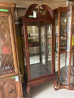Full front view of cherry wood display cabinet showing glass panels, mirrored back and interior shelves