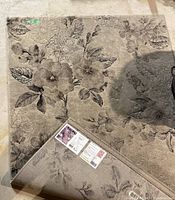 Top view of the carpet showing floral pattern and corner turned over to reveal the backing and label.