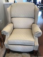 Front view of the fabric upholstered reclining chair showing cushioned armrests, seat, and backrest with wingback design.