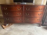 Front view of oak dresser showing six drawers and metal pulls with decorative carved accents.